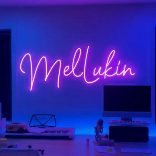 Pink Cursive LED Neon Sign saying "Mel Lukin" on a blue background