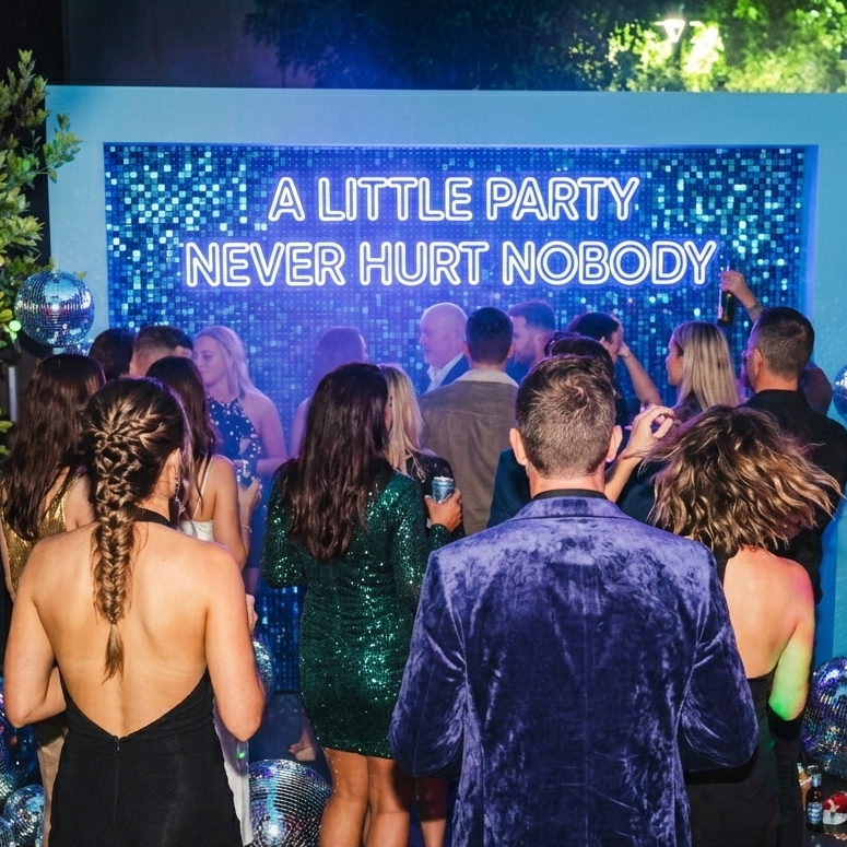 Perth, WA Party scene with people dancing in front of a screen displaying 'A LITTLE PARTY NEVER HURT NOBODY'.
