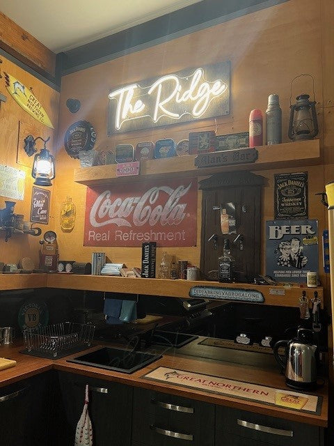 A warm white cursive font custom neon sign saying "the ridge" for Australian customers home bar