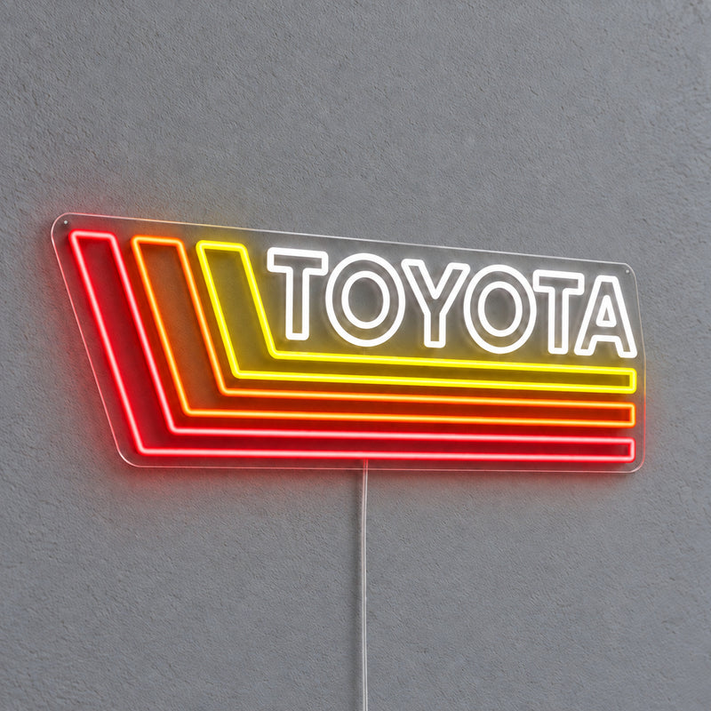 Toyota Retro Land Cruiser LED Neon Sign in white, red and yellow, featuring Toyota lettering with retro stripes on a grey wall.