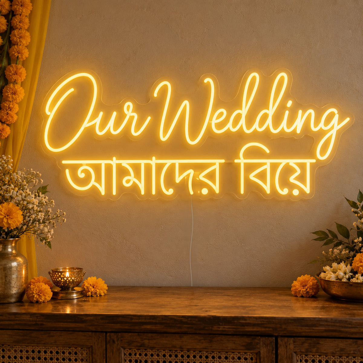 Our Wedding English & Bengali Neon Sign on clear cut-to-shape acrylic, illuminated on a wall in a styled celebration setting