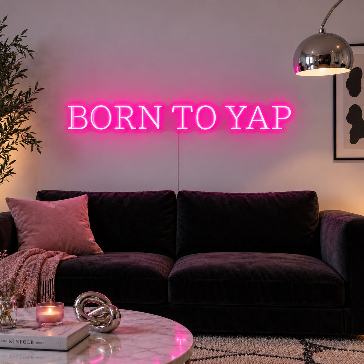 Rose Red version of the Born To Yap Neon Sign, shown above a dark sofa and glass coffee table.