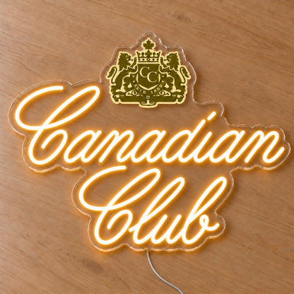 Canadian Club LED neon sign on a light wooden surface, front view