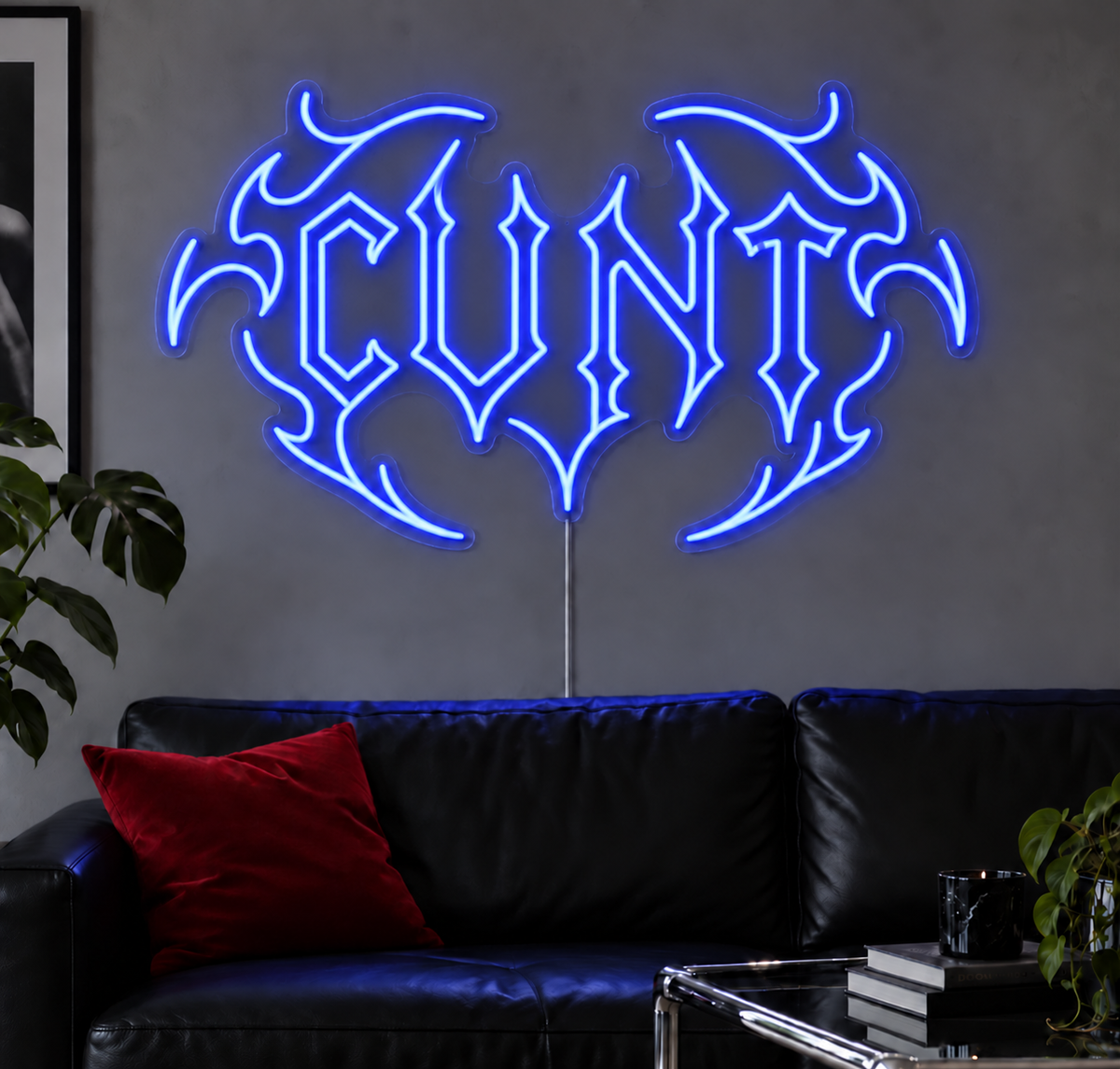 Cunt Neon Sign in Blue LED neon with double outlined C, displayed above a black leather sofa.