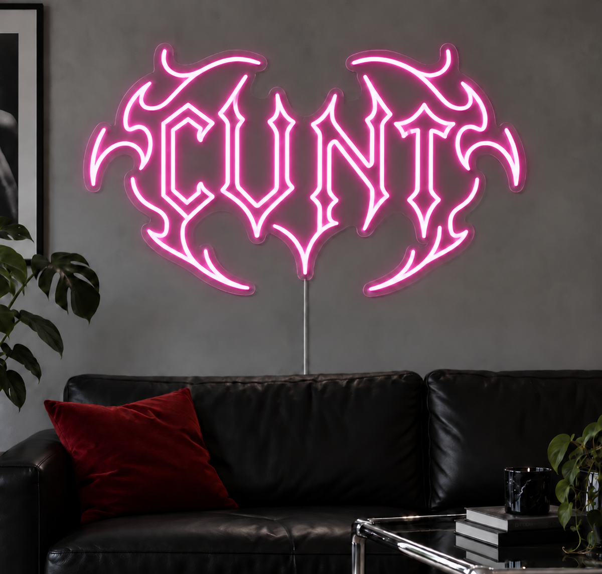 Cunt Neon Sign in Pink LED neon with double outlined C, displayed above a black leather sofa.