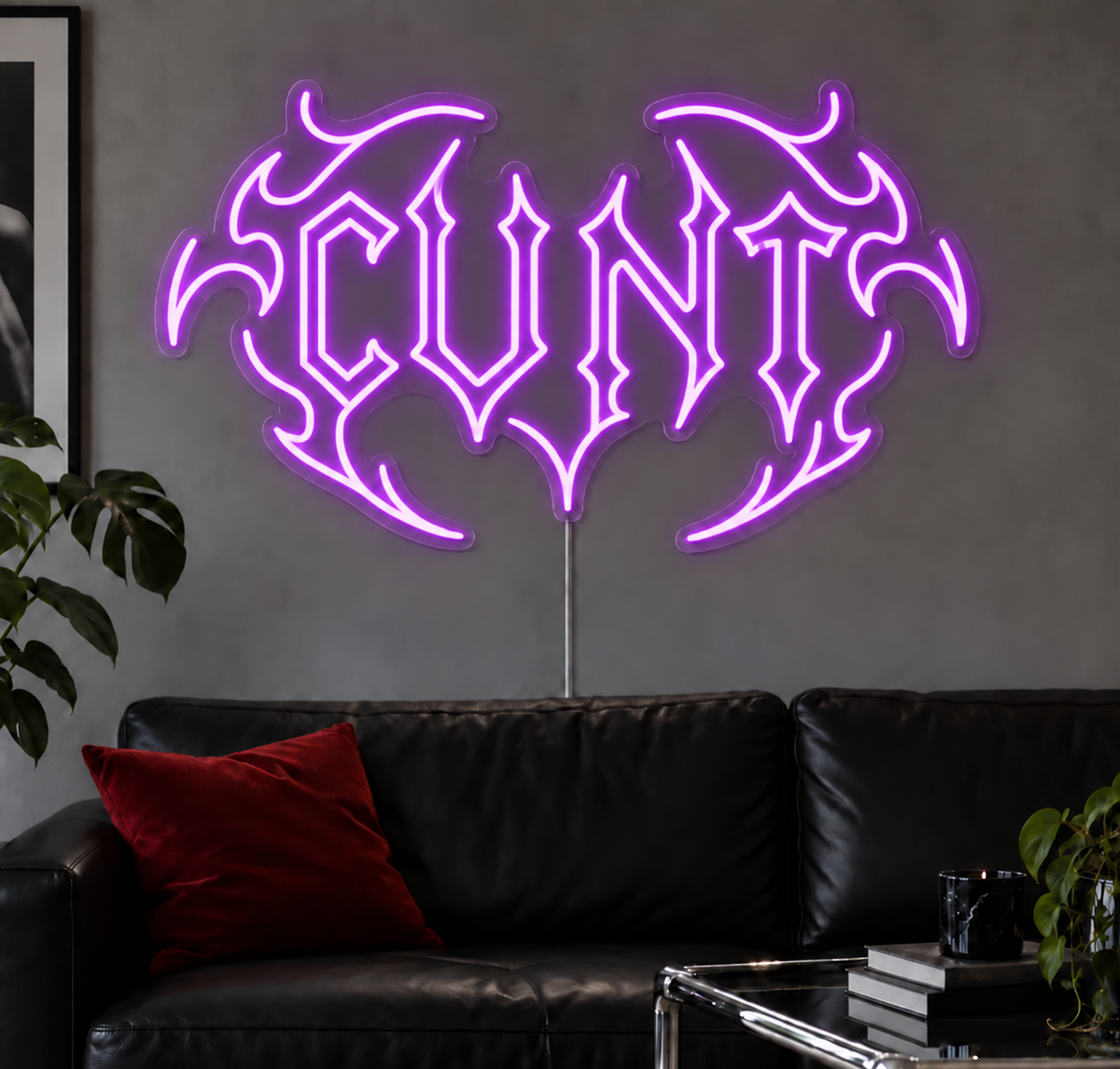 Cunt Neon Sign in Purple LED neon with double outlined C, displayed above a black leather sofa.