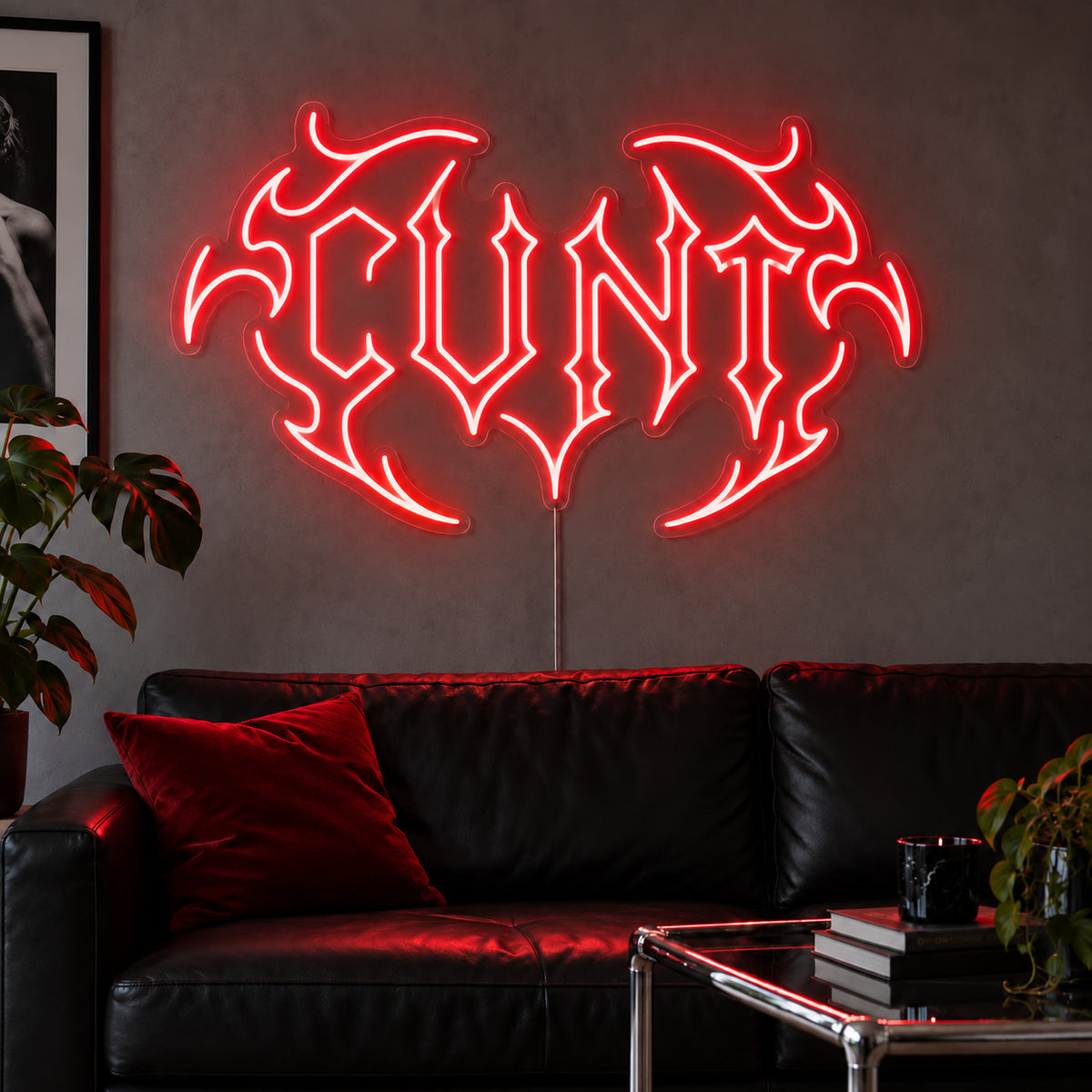 Cunt Neon Sign with red lighting, displayed in a tribal design above a black leather sofa.