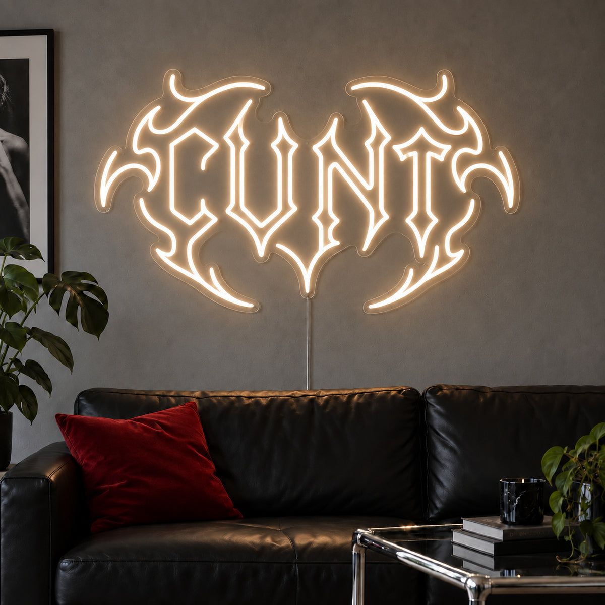 Warm White version of the Cunt Neon Sign, shown in a tribal design above a black leather sofa.