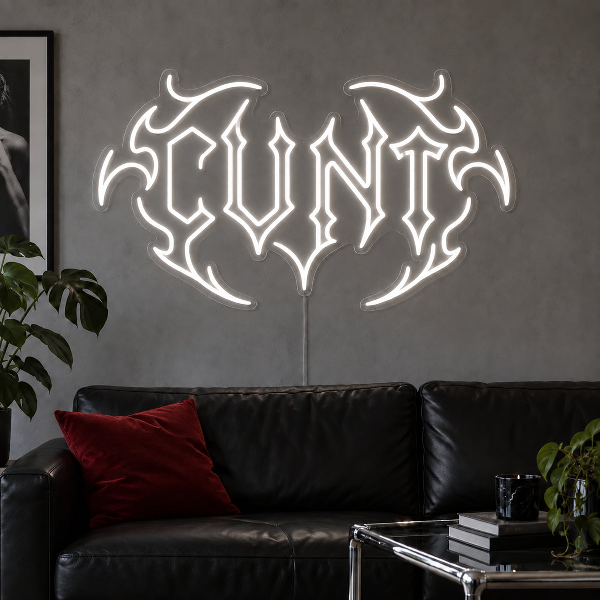 Cunt Neon Sign in white in a tribal design above a black leather sofa.