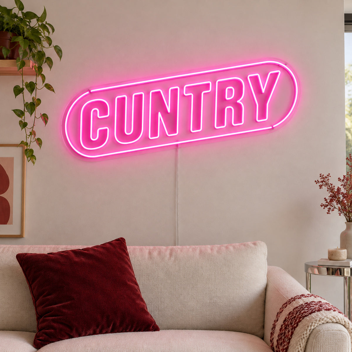 Cuntry Neon Sign glowing pink inside a rounded border above a cream sofa.
