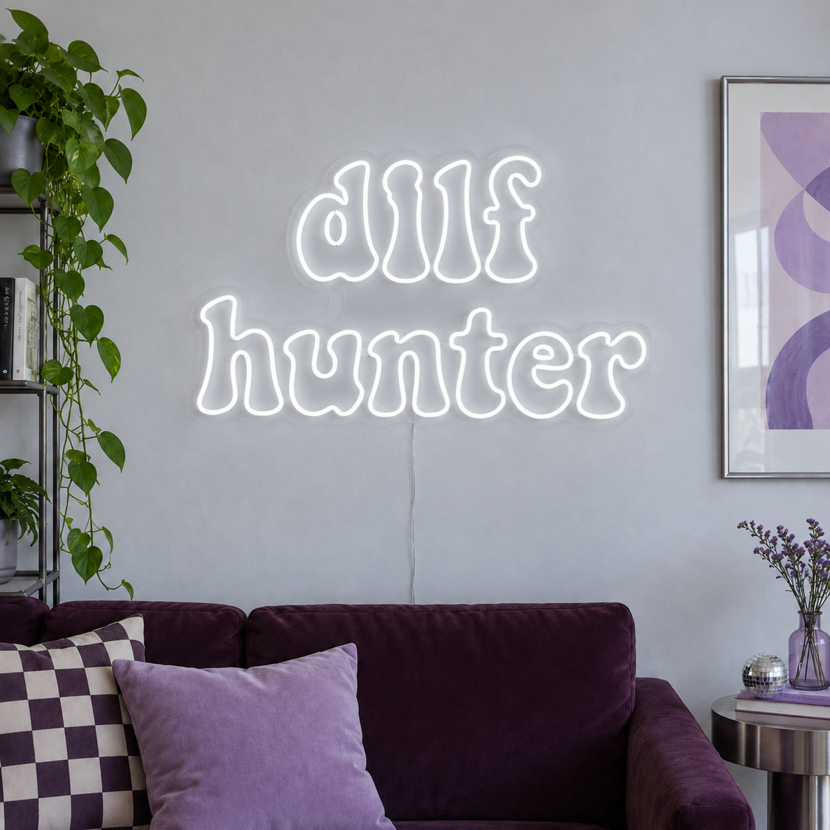 DILF Hunter Neon Sign glowing white above a sofa with purple cushions.