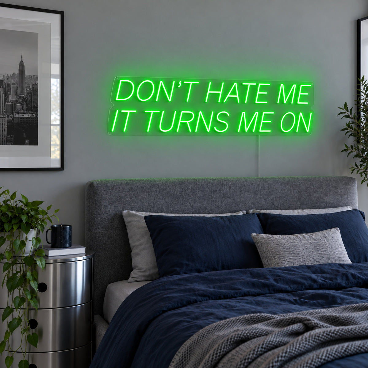 Don't Hate Me It Turns Me On Neon Sign with green lighting, displayed above a bed with dark blue bedding.
