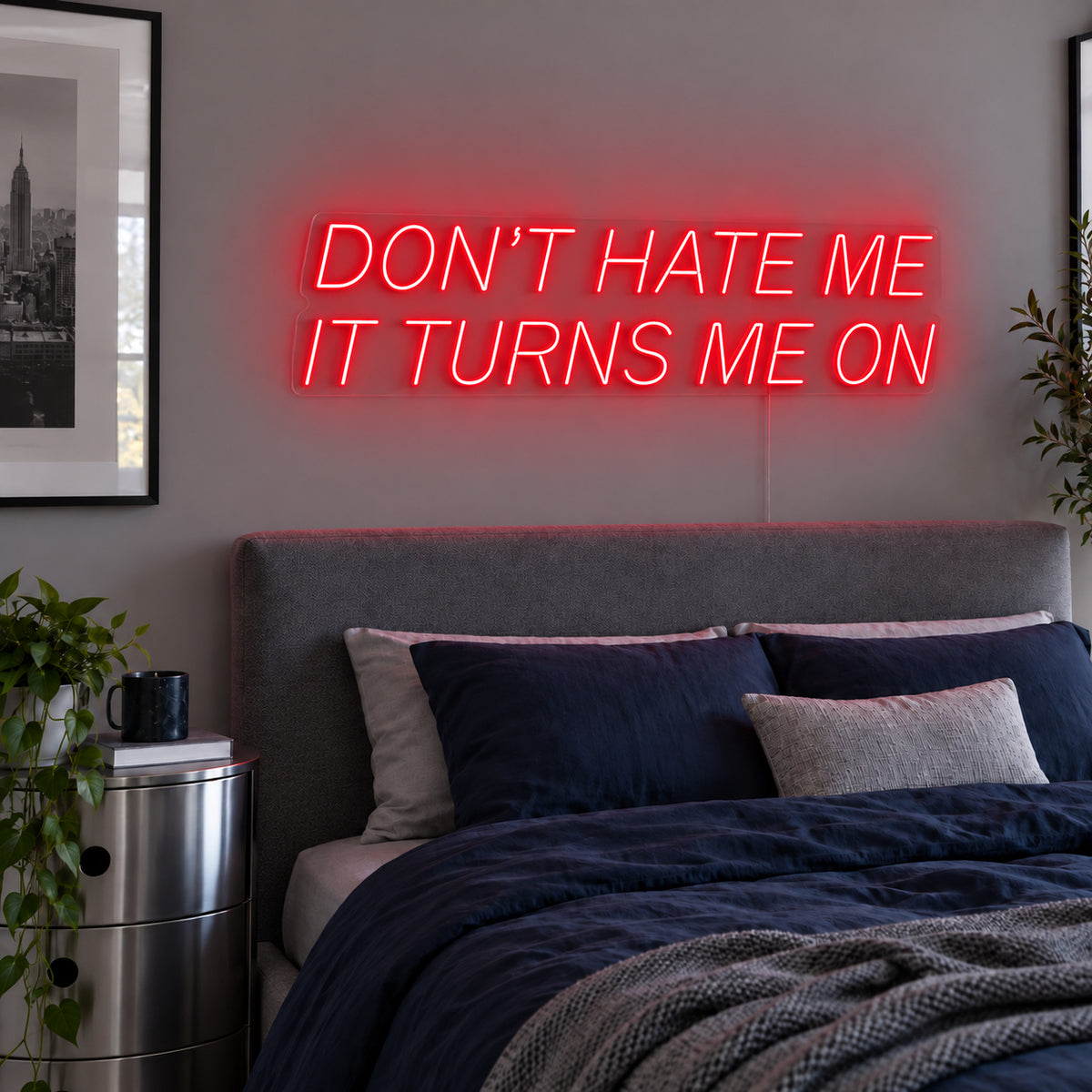 Don't Hate Me It Turns Me On Neon Sign with red lighting, displayed above a bed with dark blue bedding.