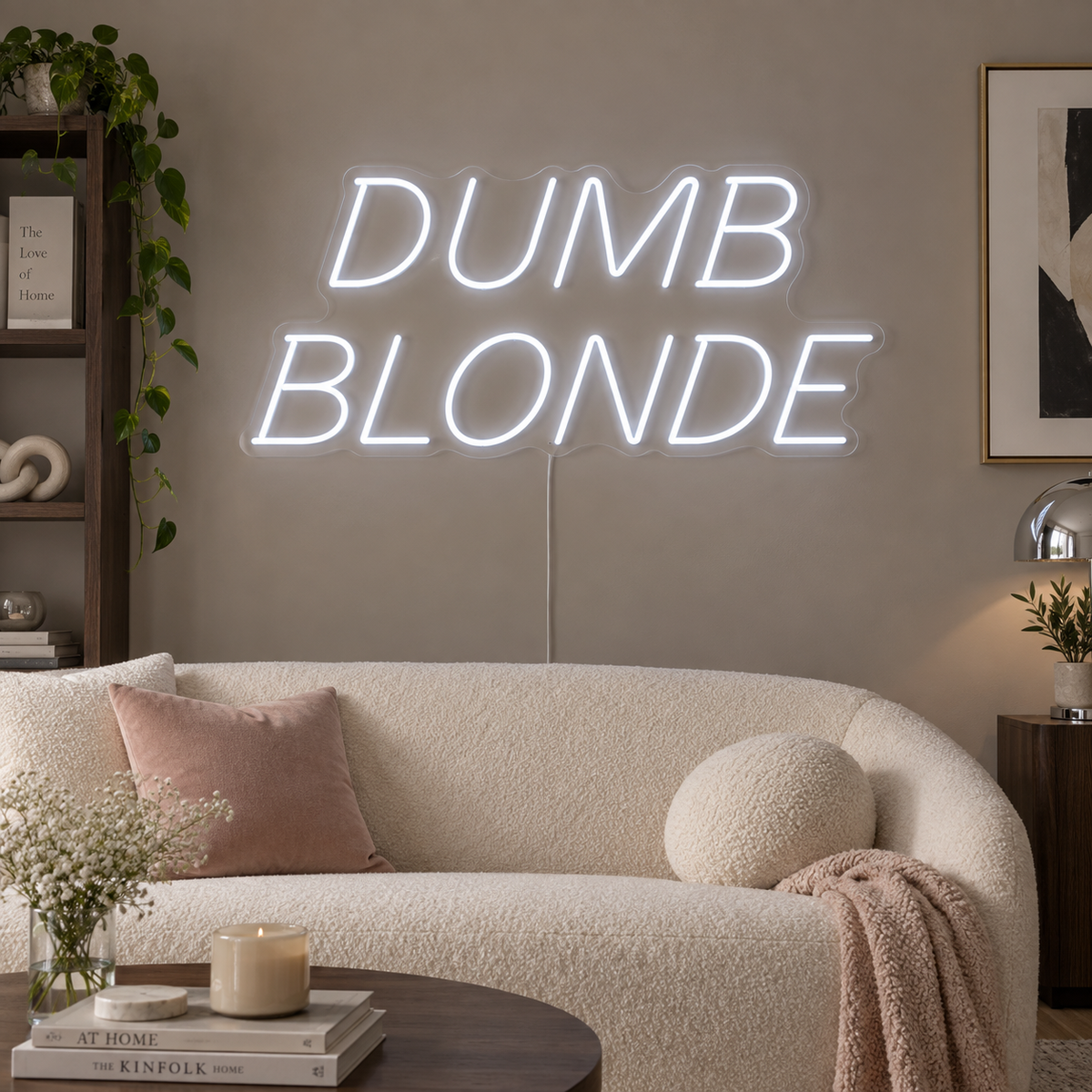 Dumb Blonde Neon Sign in white in slanted lettering above a cream sofa.