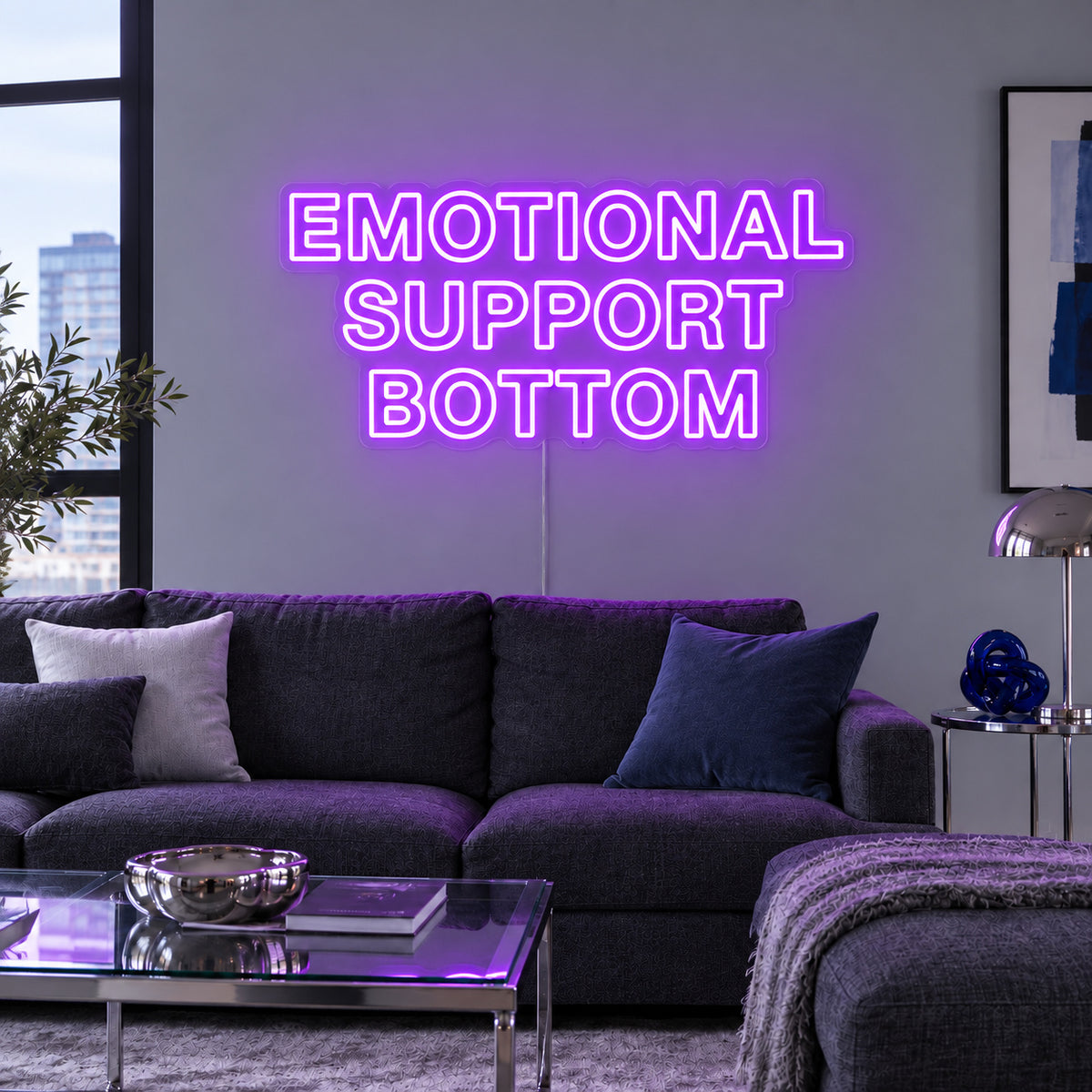 Emotional Support Bottom Neon Sign with purple lighting, displayed above a charcoal sofa.