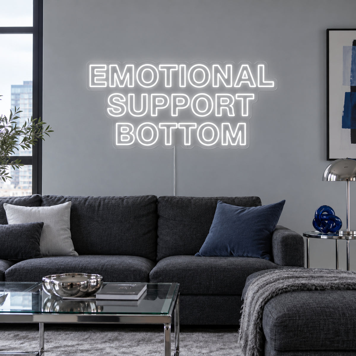 Emotional Support Bottom Neon Sign, RGB colour-changing option shown in white above a charcoal sofa.