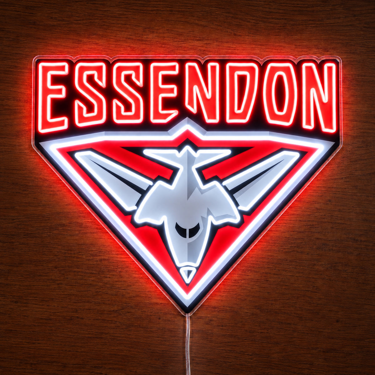 Essendon Bombers neon sign glowing brightly on a wooden surface in dim lighting