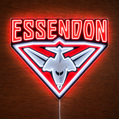 Essendon Bombers neon sign glowing brightly on a wooden surface in dim lighting