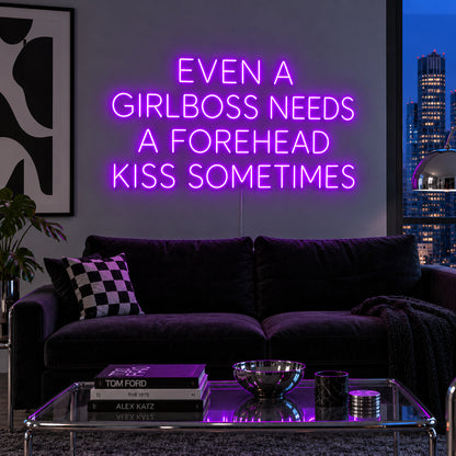 Even A Girlboss Needs A Forehead Kiss Sometimes Neon Sign with purple lighting, displayed above a dark sofa and mirrored coffee table.