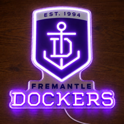 Fremantle Dockers neon sign glowing brightly on a wooden surface in dim lighting