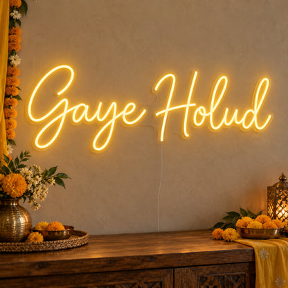 Gaye Holud Neon Sign on clear cut-to-shape acrylic, illuminated on a wall in a styled celebration setting