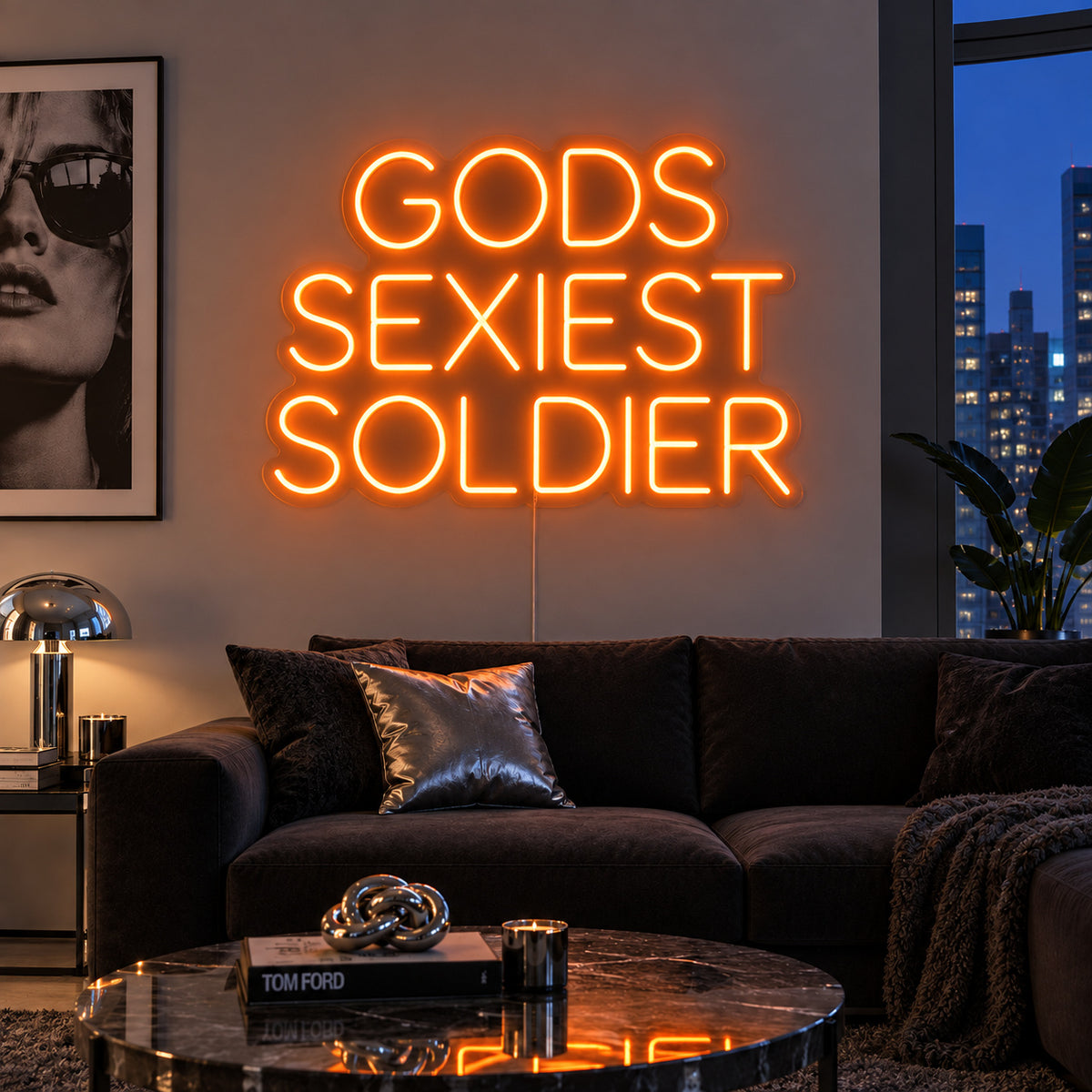 Orange version of the Gods Sexiest Soldier Neon Sign, shown in rounded lettering above a dark sofa.