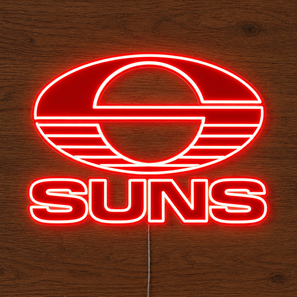 Gold Coast Suns neon sign glowing brightly on a wooden surface in dim lighting