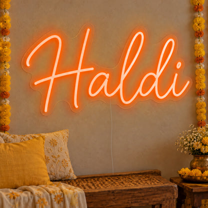 Haldi Neon Sign in orange LED neon on clear acrylic, angled view
