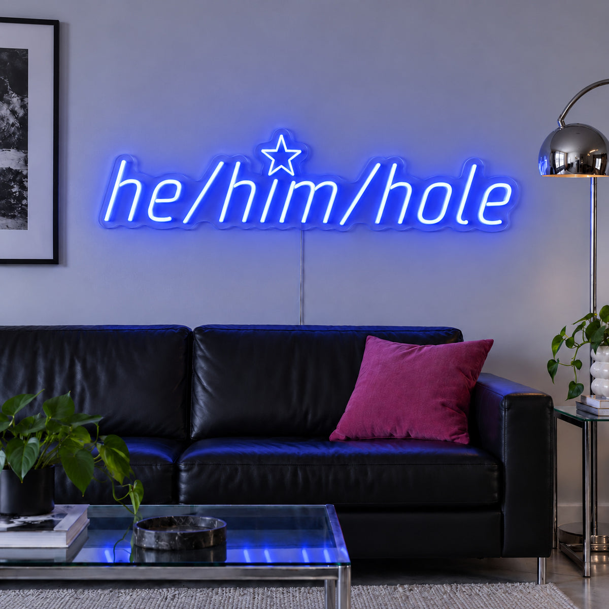 He/Him/Hole Neon Sign glowing blue above a black leather sofa.