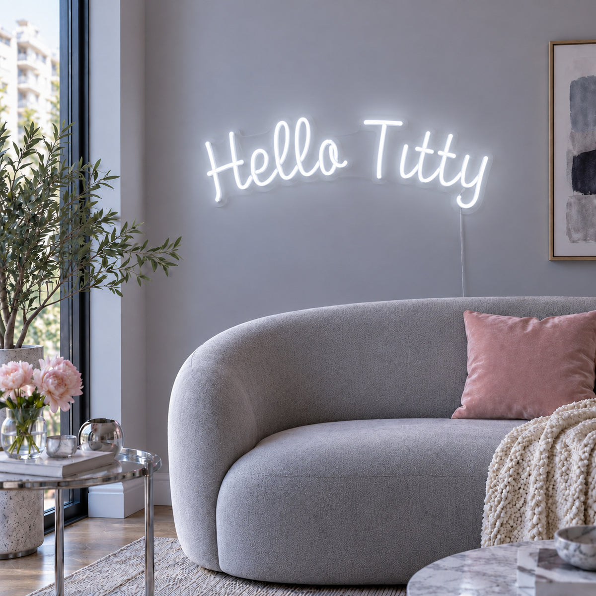 Hello Titty Neon Sign, RGB colour-changing option shown in white above a curved grey sofa.
