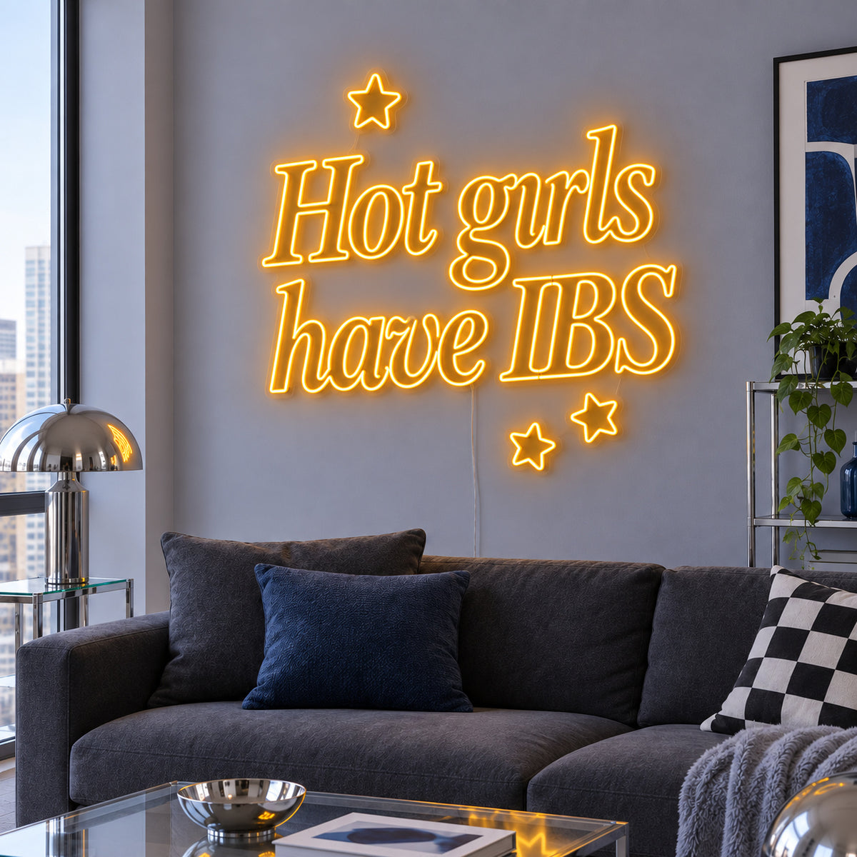 Hot Girls Have IBS Neon Sign glowing gold with star details above a charcoal sofa.