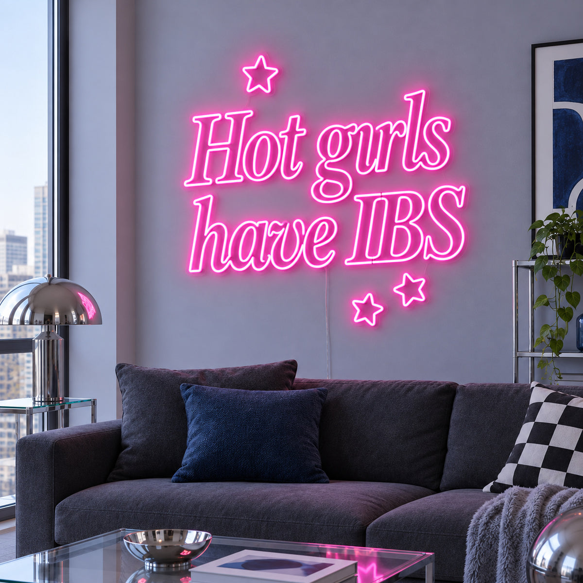 Hot Girls Have IBS Neon Sign glowing pink with star details above a charcoal sofa.