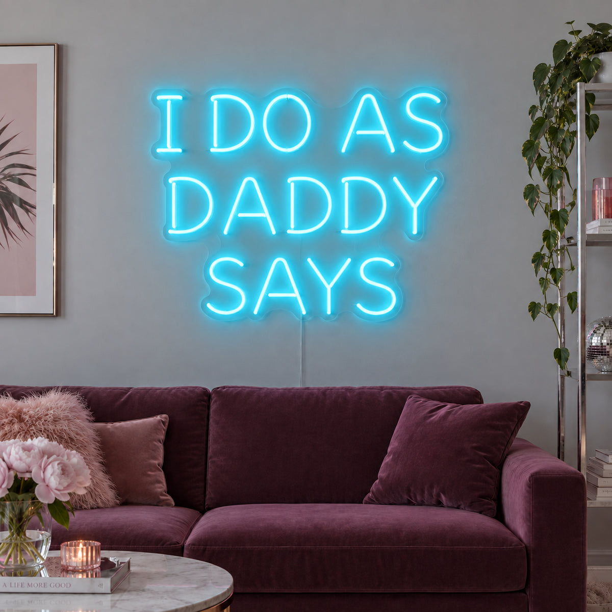 Ice Blue version of the I Do As Daddy Says Neon Sign, shown above a burgundy sofa.