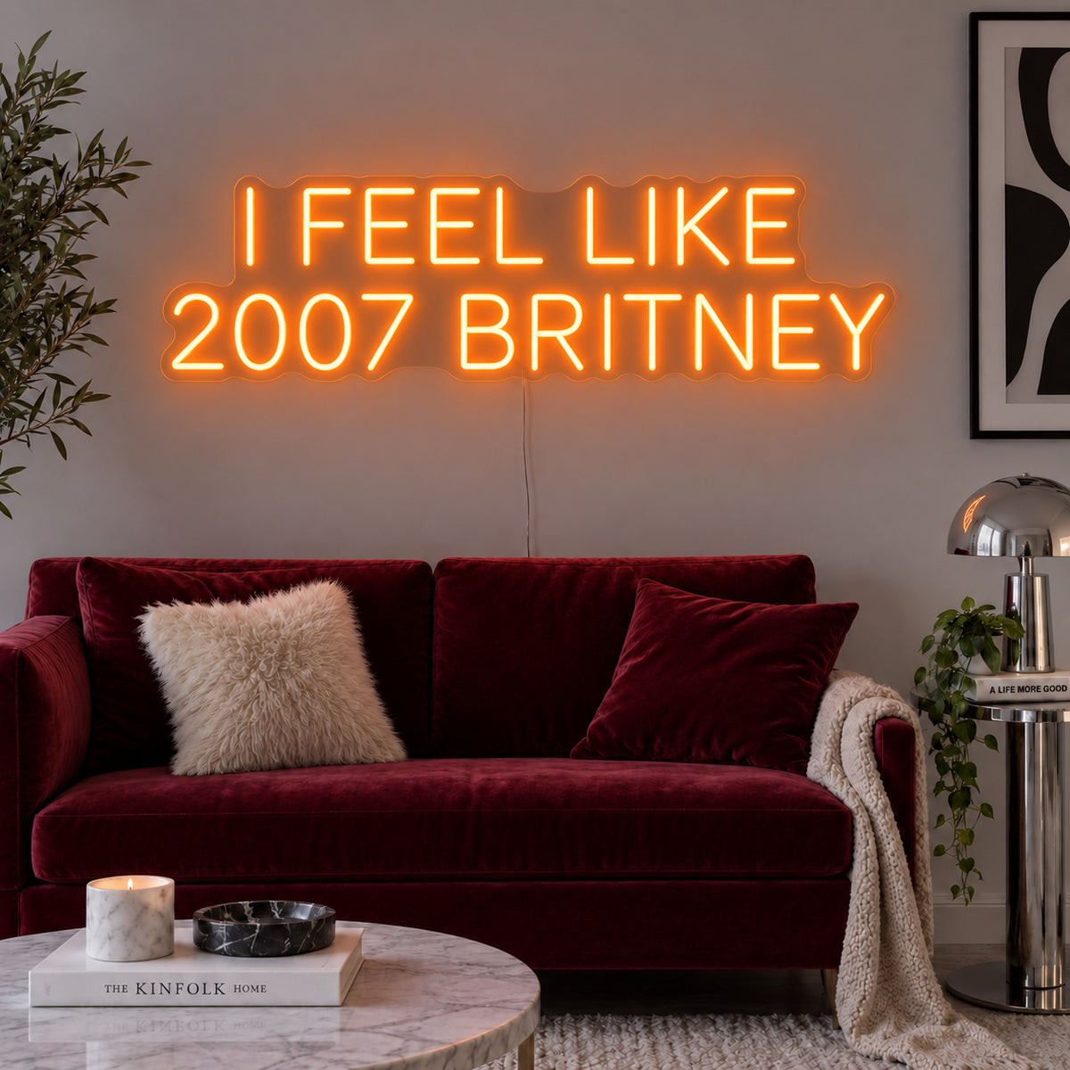 Orange version of the I Feel Like 2007 Britney Neon Sign, shown above a burgundy sofa.