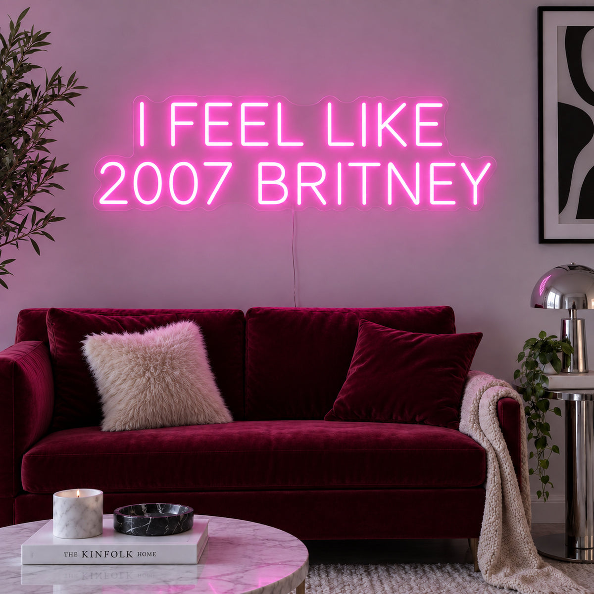 I Feel Like 2007 Britney Neon Sign glowing pink above a burgundy sofa.