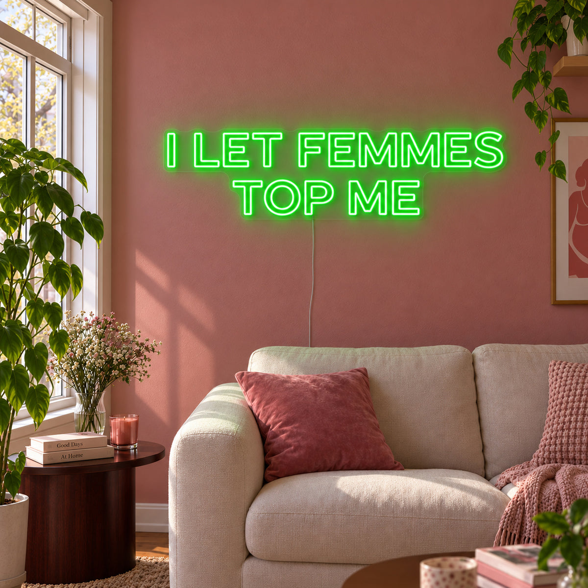 I Let Femmes Top Me Neon Sign with green lighting, displayed in outlined lettering above a cream chair.