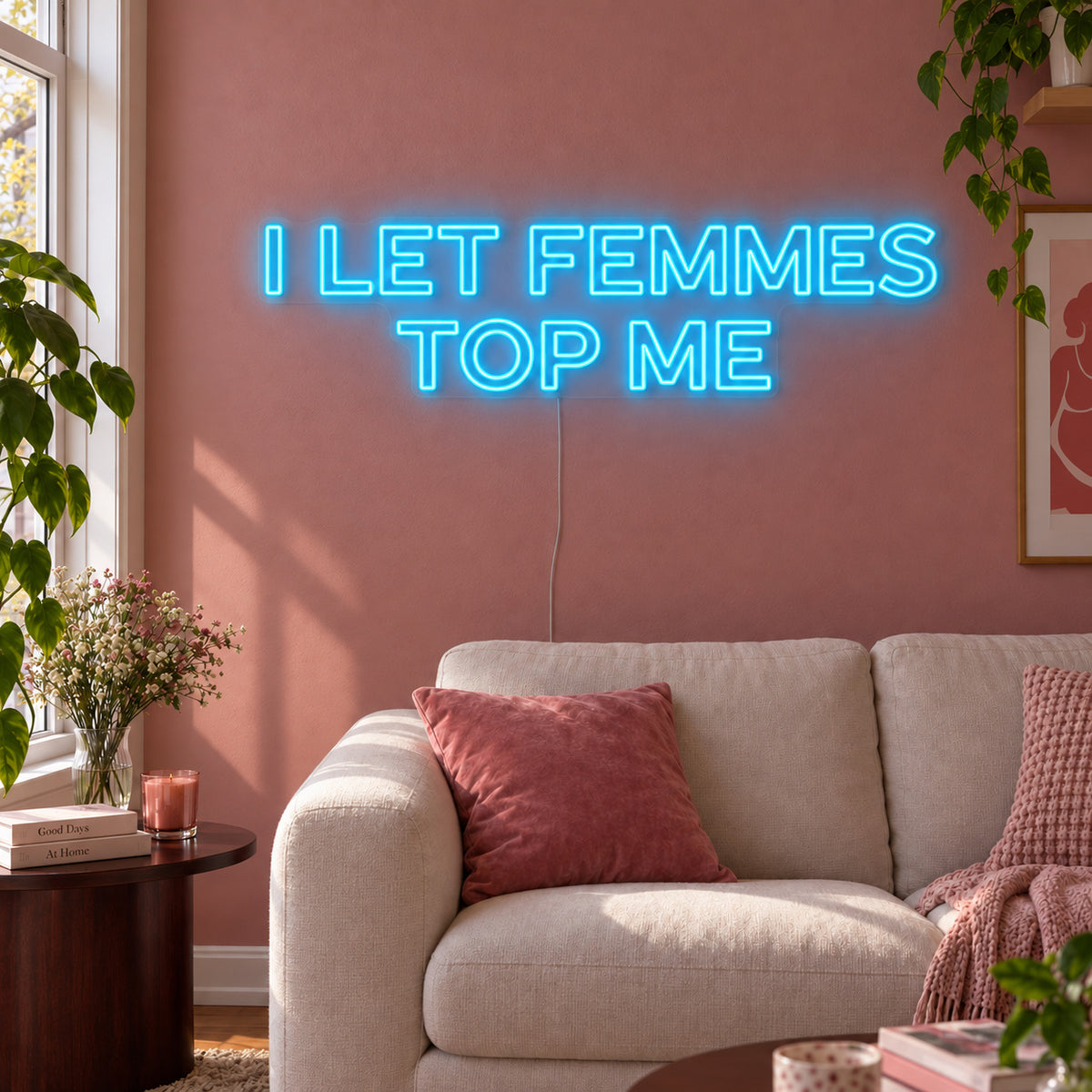 Ice Blue version of the I Let Femmes Top Me Neon Sign, shown in outlined lettering above a cream chair.