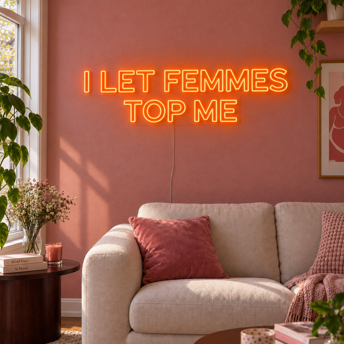 Orange version of the I Let Femmes Top Me Neon Sign, shown in outlined lettering above a cream chair.