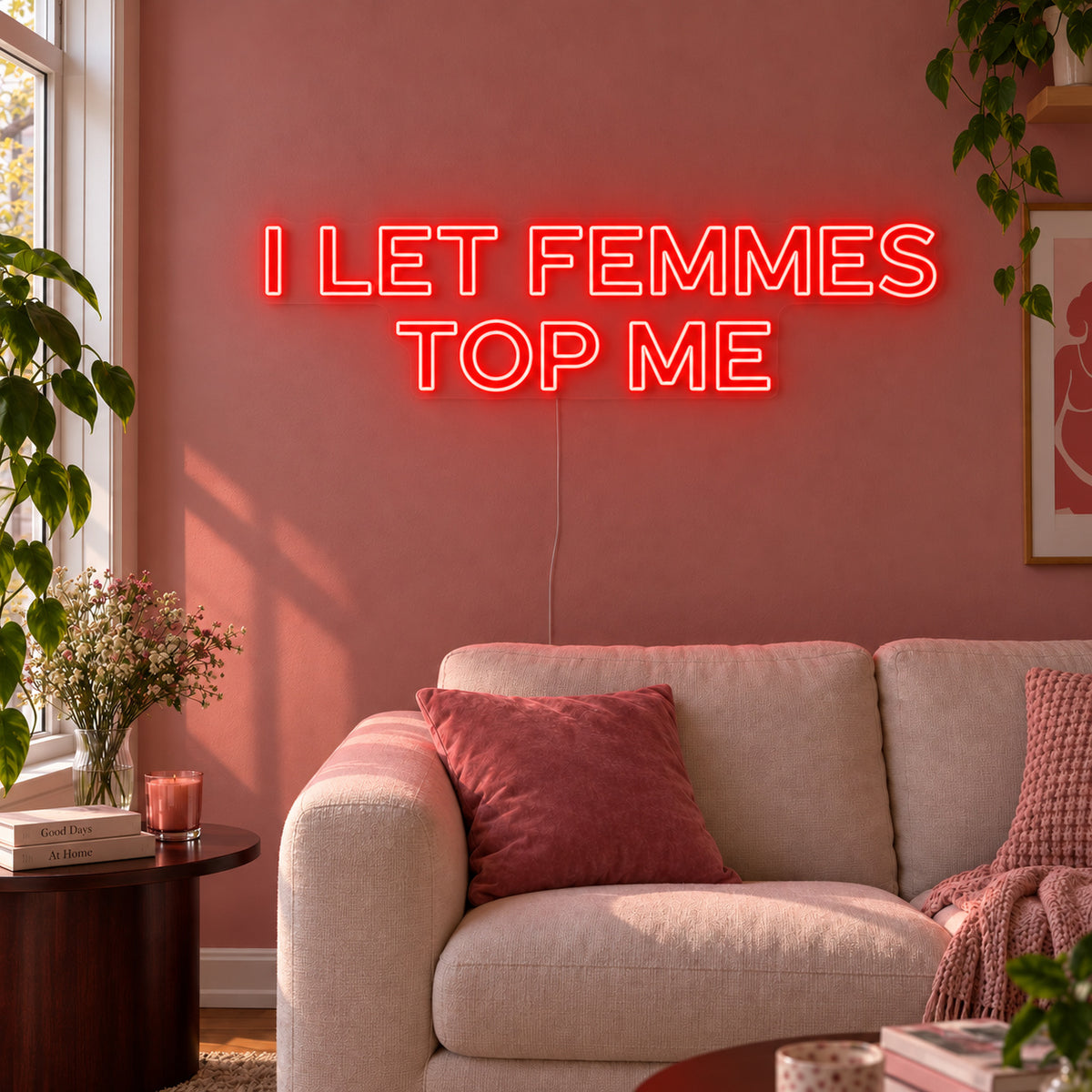 I Let Femmes Top Me Neon Sign with red lighting, displayed in outlined lettering above a cream chair.