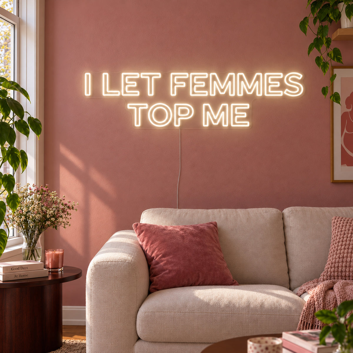 Warm White version of the I Let Femmes Top Me Neon Sign, shown in outlined lettering above a cream chair.