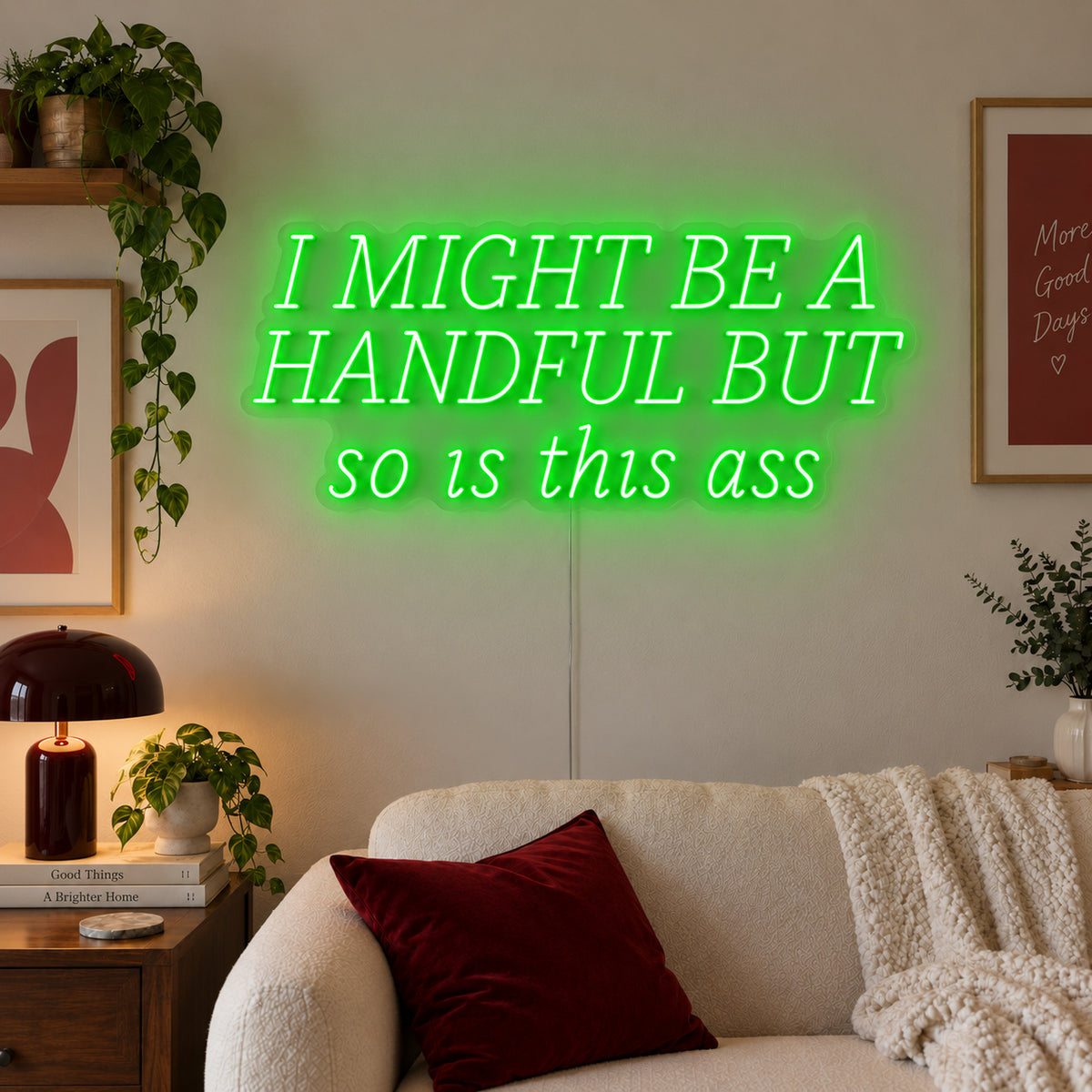 I Might Be A Handful But So Is This Ass Neon Sign with green lighting, displayed in wide lettering above a cream sofa.