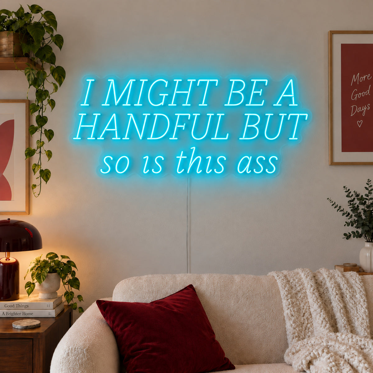 Ice Blue version of the I Might Be A Handful But So Is This Ass Neon Sign, shown in wide lettering above a cream sofa.