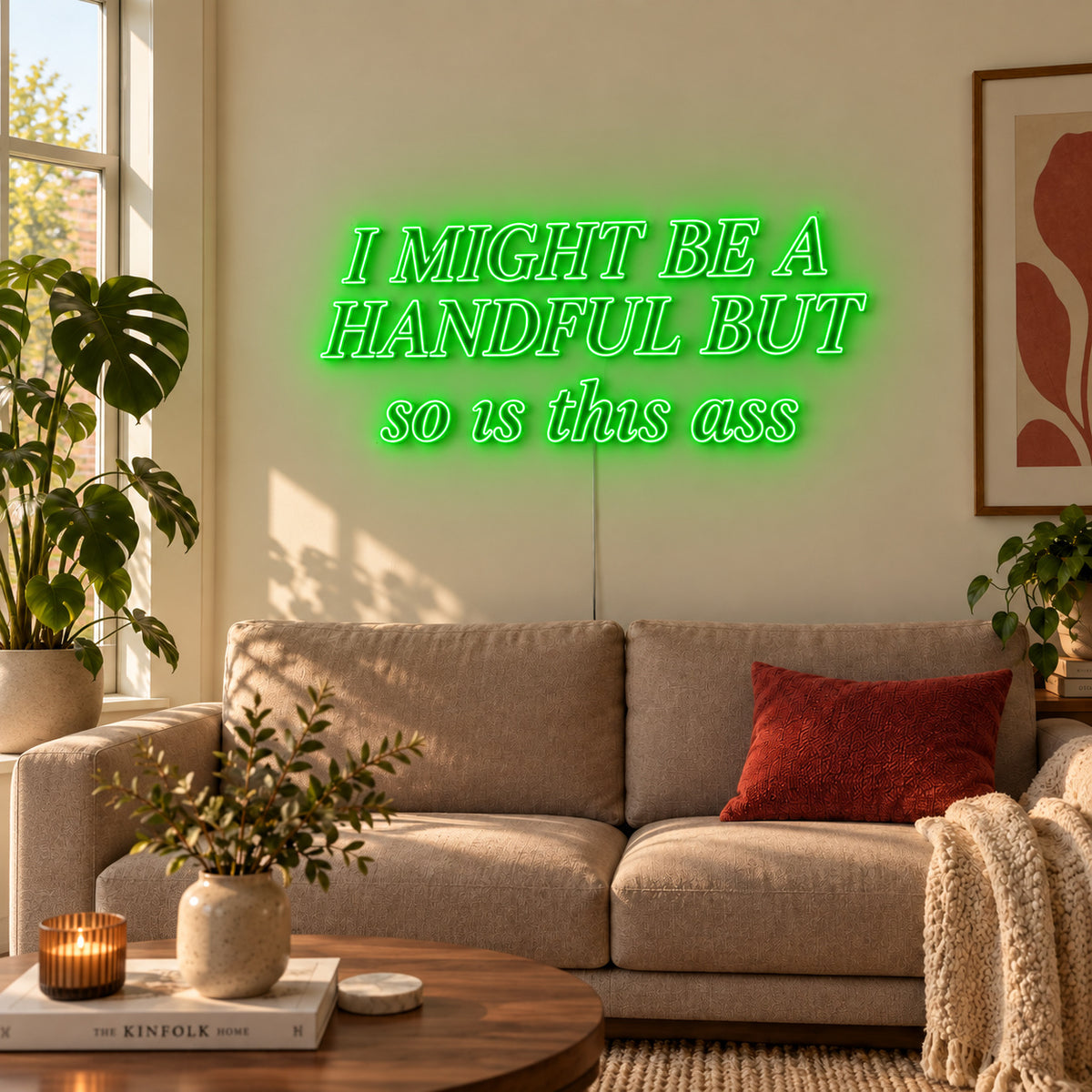I Might Be A Handful But So Is This Ass Neon Sign with green lighting, displayed in compact lettering above a cream sofa.