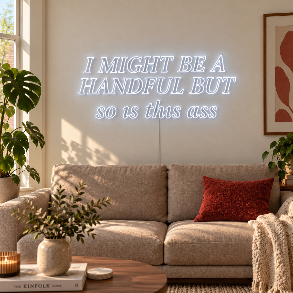 I Might Be A Handful But So Is This Ass Neon Sign, RGB colour-changing option shown in white in compact lettering above a cream sofa.