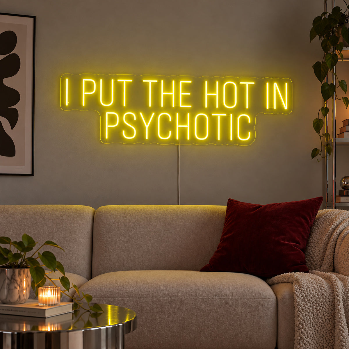 I Put The Hot In Psychotic Neon Sign with yellow lighting, displayed above a neutral sofa.