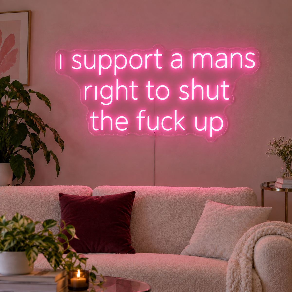 I Support A Mans Right To Shut The Fuck Up Neon Sign glowing pink above a cream sofa.