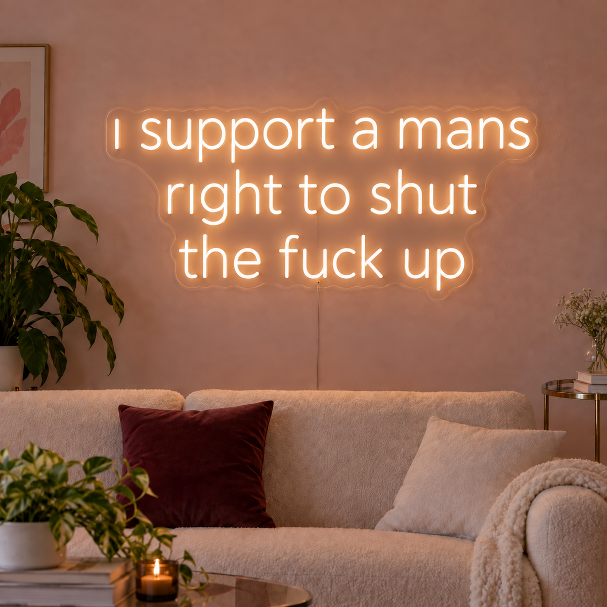 I Support A Mans Right To Shut The Fuck Up Neon Sign in warm white above a cream sofa.