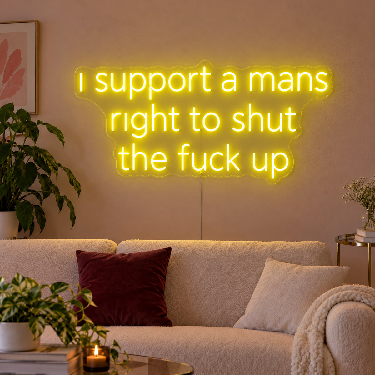I Support A Mans Right To Shut The Fuck Up Neon Sign with yellow lighting, displayed above a cream sofa.
