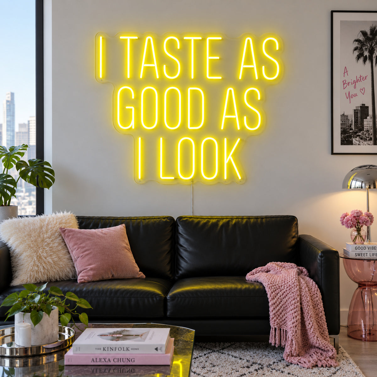 I Taste As Good As I Look Neon Sign with yellow lighting, displayed above a black sofa.