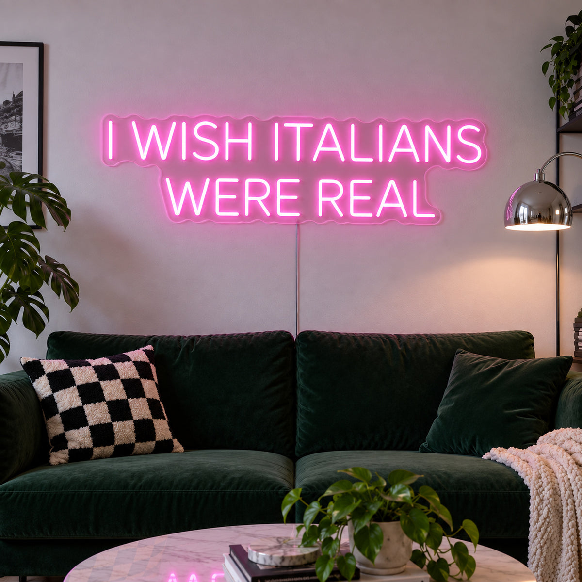 I Wish Italians Were Real Neon Sign glowing pink above a green sofa.